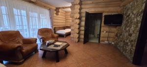 a living room with leather furniture and a tv at Фільварок Кмитів in Kosharishche