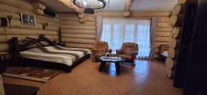 a bedroom in a log cabin with a bed and a table at Фільварок Кмитів in Kosharishche