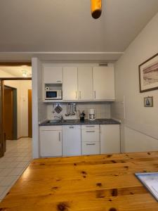 a kitchen with white cabinets and a wooden floor at Ferienwohnungen Alte Schmiede 9 in Norderney +1 photo