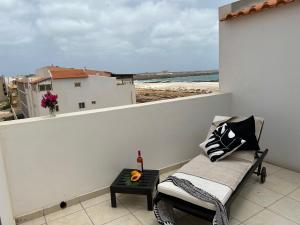 Un balcón con un banco y vista a la playa. en Un hogar lejos de tu hogar, en Sal Rei