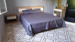 a bedroom with a bed and a tiled floor at La Villa Émeraude in Mbachilé