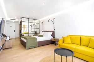 a bedroom with a bed and a yellow couch at Olive Villas Beach Hotel in Sozopol
