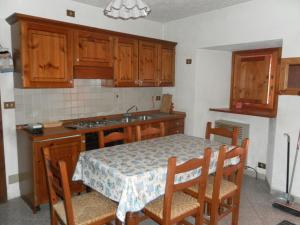 - une cuisine avec une table, des chaises et un évier dans l'établissement Appartamento Stile Alpino, à Lignan