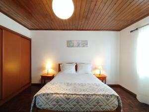 a bedroom with a bed with two lamps on two tables at Casa do Cruzeiro in Lagoa