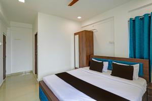 a bedroom with a large bed with blue curtains at Super Collection O Besa Square Nagpur Formerly Yuva Inn in Nagpur