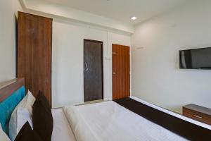 a bedroom with a bed and a flat screen tv at Super Collection O Besa Square Nagpur Formerly Yuva Inn in Nagpur +23 photos