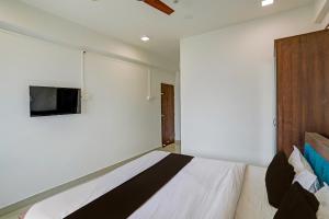 a bedroom with a bed and a tv on the wall at Super Collection O Besa Square Nagpur Formerly Yuva Inn in Nagpur