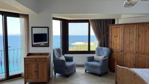 a bedroom with two chairs and a tv and a balcony at Nergis Hotel in Karaburun