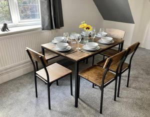 een eettafel met stoelen, borden en glazen bij Brackens House Brentwood in Little Warley +17 foto's