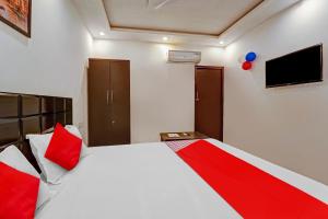 a bedroom with a bed with red pillows and a television at Hotel O Elite Inn in Dānāpur +31 photos