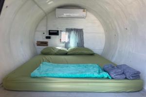a bed in a small room with two pillows at Kua Car Camp in Lampang