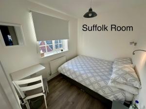 a small bedroom with a bed and a desk at Chez Ana in Saxmundham