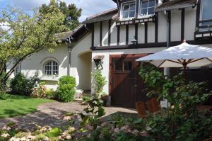 a white house with an umbrella in the yard at Maison d'hôtes Paris Riverside in Saint-Maur-des-Fossés