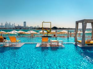 a pool with chairs and a swing in the water at C Central Hotel and Resort The Palm in Dubai
