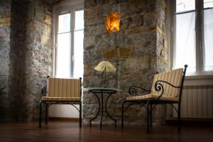 two chairs and a table in a room with a stone wall at Residence Theresia- Tailor Made Stay in Trieste