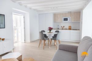 a white kitchen and dining room with a table and chairs at Villalobos by Cadiz Time in Cádiz