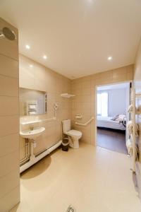 a bathroom with a sink and a toilet and a bed at LOGIS HOTEL - Le Petit Bellon in Senlis +30 photos
