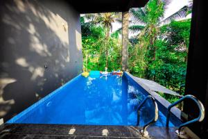 a blue swimming pool with trees in the background at La Vista Resorts in Wayanad
