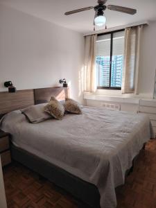 Schlafzimmer mit einem Bett, einem Deckenventilator und einem Fenster in der Unterkunft Apartapunta in Punta del Este