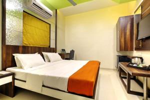 a bedroom with a large bed and a desk at Hotel Lonavla in Lonavala