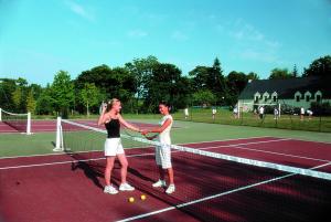 two women shaking hands over the net on a tennis court at VTF Ker Belen in Riec-sur-Bélon