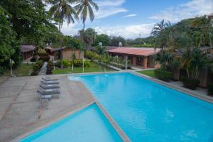 a large blue swimming pool with chairs and a building at Hotel Las Espuelas, Bar & Restaurant in Liberia