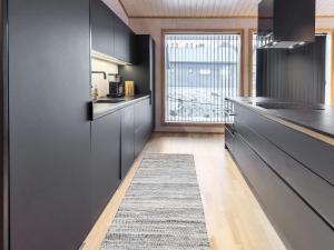 a kitchen with black cabinets and a rug on the floor at Holiday Home Villa plywood by Interhome in Syöte