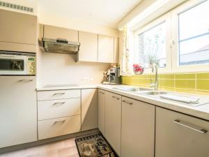 a kitchen with white cabinets and a sink and a window at Apartment Zeelucht with private garden by Interhome in De Haan