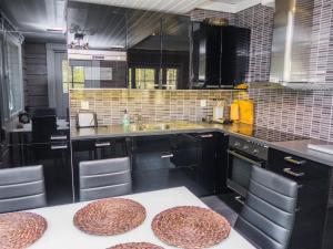 eine Küche mit schwarzen Schränken und einem Waschbecken mit Hockern in der Unterkunft Holiday Home Kiehtäjän kuohu by Interhome in Käylä + 15 Fotos