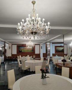 una sala da pranzo con tavoli bianchi e un lampadario di Hotel Mio City a Kula