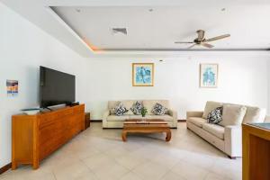 a living room with a couch and a flat screen tv at Surin villa by Pattara in Ban Lum Fuang