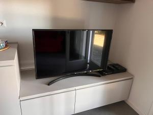 a flat screen tv sitting on top of a cabinet at Villa Santa Chiara Lesa - appartamento vista lago con piscina in Lesa