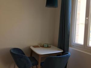 a small table with two blue chairs and a window at L'Elégante in Fécamp