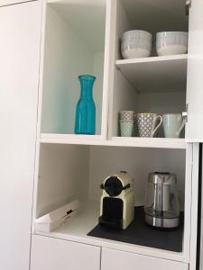 a white cabinet with a blue vase and cups at L'Elégante in Fécamp