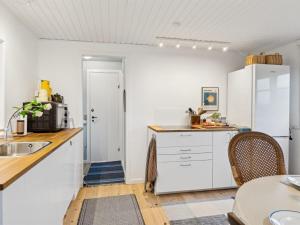 una cucina con mobili bianchi, tavolo e sedie di Holiday Home Dufa - 200m to the inlet by Interhome a Føllenslev Altre 29 foto