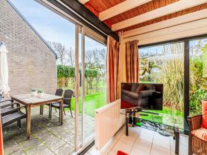 a living room with a television and a table with a television screen at Holiday Home Buitenplaats Schouwen nr 86 by Interhome in Burgh Haamstede
