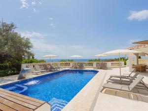 a swimming pool with chairs and umbrellas at Villa Villa Maitreya by Interhome in Son Bou +42 photos