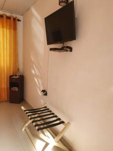 a room with a chair and a tv on the wall at Rare Lodge in Kandy