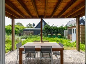 a wooden table and chairs under a wooden roof at Holiday Home Horizon- Sea & Sun by Interhome in Renesse