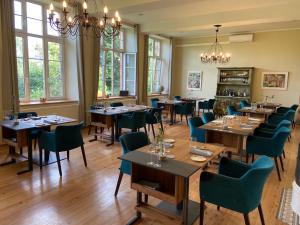 a dining room with tables and chairs and windows at Restaurant und Hotel Alte Schule Fürstenhagen in Fürstenhagen