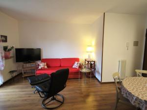 Una sala de estar con un sofá rojo y un televisor. en Apartment Magnolia by Interhome, en Porto Valtravaglia