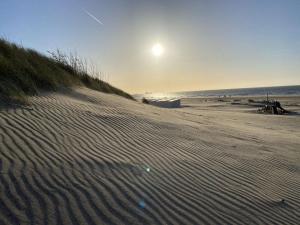einen Sandstrand mit aufgehender Sonne über dem Meer in der Unterkunft Holiday Home Seascape Wellness Nieuwvliet-Bad by Interhome in Nieuwvliet-Bad