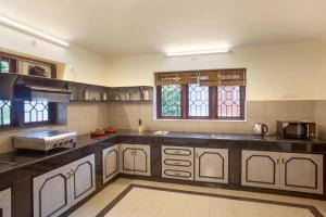 a large kitchen with black counter tops and windows at Away From Home - 2 - Home Stay Ooty, Entire 4BHK Villa in Ooty