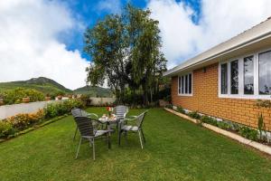 a table and chairs on a lawn in front of a house at Away From Home - 2 - Home Stay Ooty, Entire 4BHK Villa in Ooty