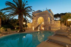 a large house with a swimming pool with a palm tree at Villa Angelina in Selva di Fasano