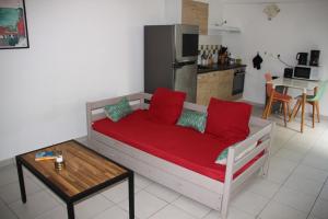 a couch with red pillows in a kitchen with a table at Location Beauséjour avec Jacuzzi Sainte-Anne Le Helleux in Sainte-Anne