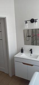 a white bathroom with a sink and a mirror at Studio Żdanowska Zamość in Zamość