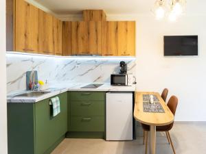 a kitchen with green cabinets and a small table at Oasis Apartments Maggana Xanthi in Xanthi