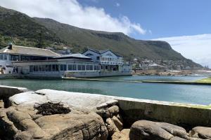 a building next to a body of water with mountains at Cape Town Explorer's Rest in Meadowridge