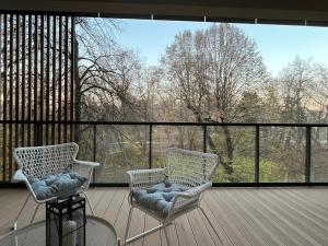 ウッチにあるPark Zen, taras i widok na parkの大きな窓のあるデッキに椅子2脚